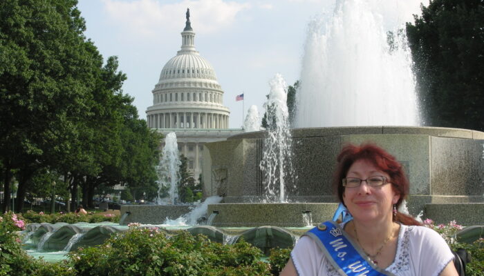 Board member Marie Clement, 2009 MS Wheelchair Kansas; visiting DC A person wearing a sash in front of the United States Capitol